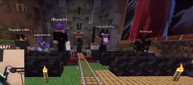 A screenshot of Tubbo's stream showing a gathering of players in a stone nook of sorts on the server. There are black benches where Hbomb, Jack Manifold, Sam, Ant, and Puffy all sit along. At the front, behind the pulpit, stands Bad. There is a railroad track leading down the center aisle, presumably for the body to roll along. Various pictures and posters of Schlatt hang on the walls around the place.